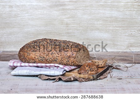 Loaf of bread with seeds wrapped in cloth over wooden background and copy space