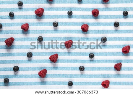Fresh berries in lines over blue and white background