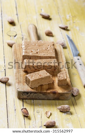 Turron, typical Spanish Christmas dessert for Christmas served in a wooden table over yellow background