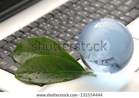 Crystal earth and green leaves on laptop, global business and ecology image
