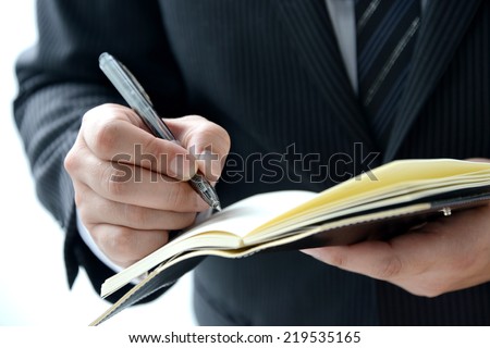 Business person writing on personal organizer