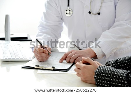 Doctor writing medical record and explaining for patient