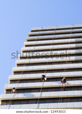 abseiling window cleaners series - portrait orientation frontal view of building with 3 window cleaners dangling
