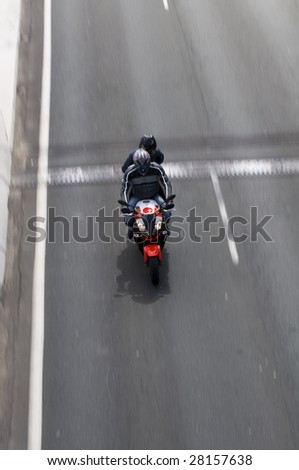 Motorcyclist speeding down road with a passenger on the back taken from above