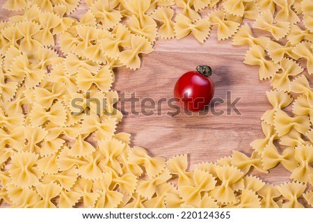 Uncooked pasta farfalle on a wooden board