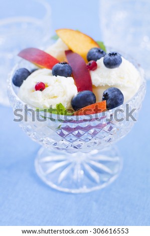 Crystal ice-cream bowl filled with vanilla ice cream, blueberries and nectarines