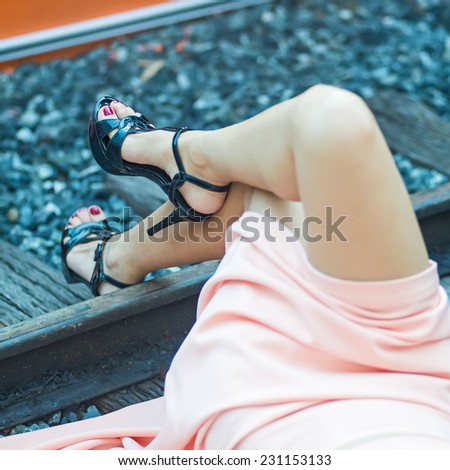 Woman legs in black high heels lying on the ground.