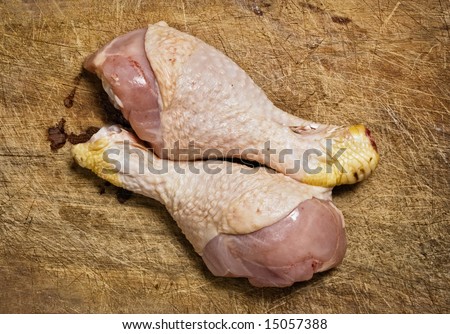 Raw chicken legs on old wooden table.