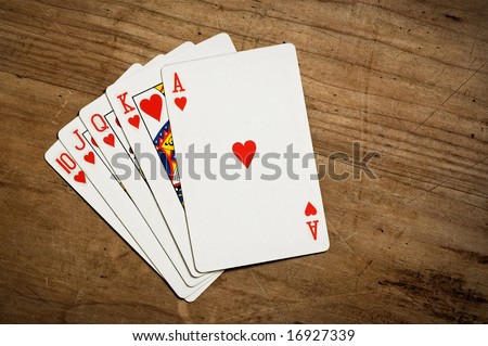 Royal flush poker hand on an old scratched table with copy space. Hearts.