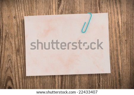 Paper note with clip on old wooden table, clipping path.