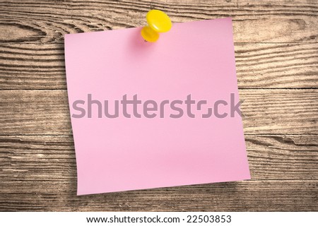 Pink paper note with thumbtack on wooden surface, clipping path.