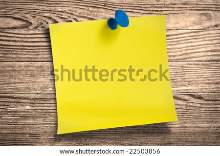 Yellow paper note with thumbtack on wooden surface, clipping path.