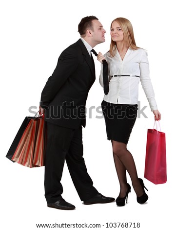 Image of a young couple with shopping bags having fun while the woman pulls her boyfriend tie for a kiss.