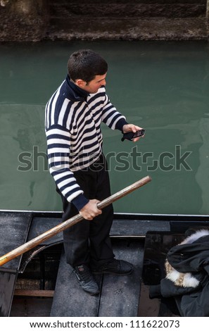 VENICE,ITALY-FEBRUARY 25: Upper view of an unidentified gondolier checking the mobile phone in his gondola on February 25, 2011.Gondola is a major mode of touristic transport in Venice, Italy.