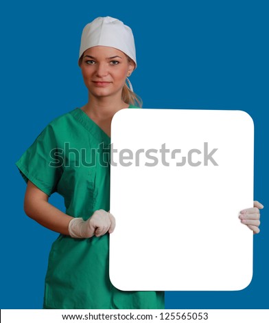 A young woman doctor holding an empty white bill board against a blue background.