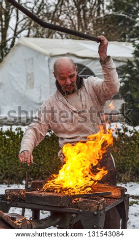 RODEMACK,FRANCE-DEC 09:Environmental portrait of a medieval blacksmith working on fire ,outdoor, during a historical reenactment festival on December 9,2012 in Rodemack in France.