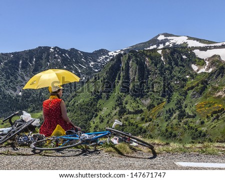 PORT DE PAILHERES,FRANCE- JUL 6: Unidentified woman with a yellow umbrella admires the landscape at the Col de Pailheres during the stage 8 of edition 100 of Le Tour de France on July 6 2013.