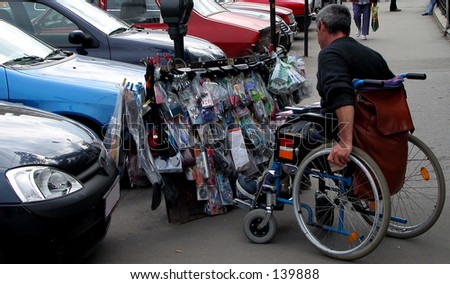 A handicapped man in wheelchair selling items in a parking.