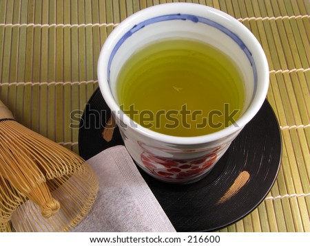 A table with a cup of tea,a bamboo tea whisk and a tea bag...Asian still life
