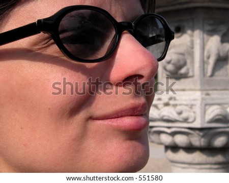Close up profile of a woman with sunglasses.In the background,blurred there is a Japanese stone lantern.Asian touristic metaphor.......