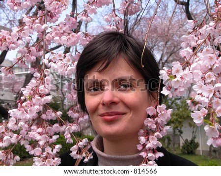 Happy woman smiling between a cherry tree flowers