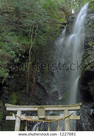Waterfall in a forest with a specific Japanese stone temple gate at the base.Location:southern part of Kyoto,Japan