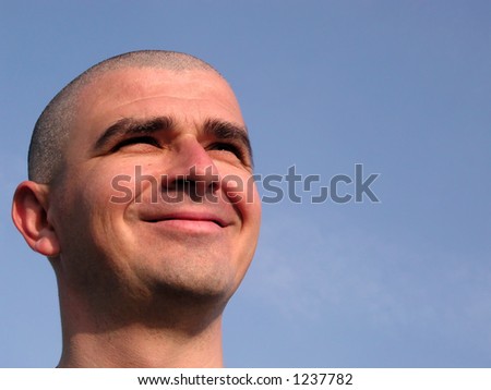 Bald head man smiling against the sun over a clean blue sky