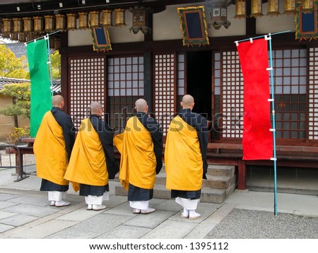 Group of four Buddhist monks praying in front of a temple in Kyoto,Japan.