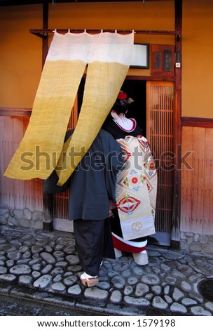 Geisha entering in a traditional wooden tea house from Gion,Kyoto,Japan.