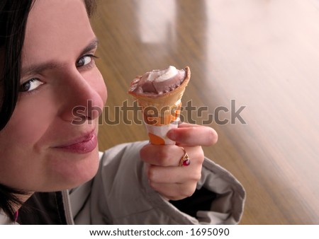 Smiling woman eating ice-cream in a coffee bar in a cold day.