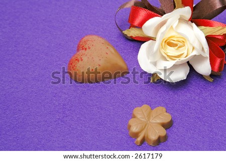 Still life with fancy Valentine chocolates and a rose over a violet background.