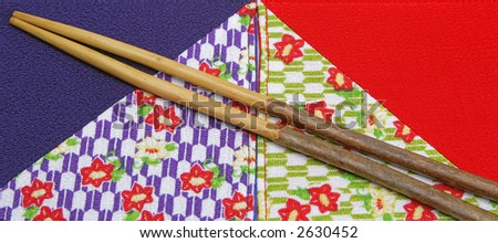 Image of two chopsticks made by cherry tree blossom on two piece of specific Japanese fabric.