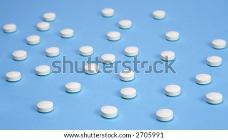 A medical background with white pills over a blue background,Selective focus on the middle pills.