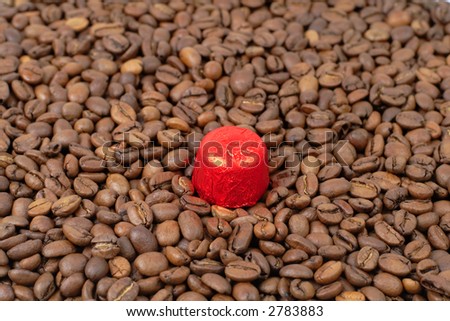 A piece of red chocolate on a coffee beans stack