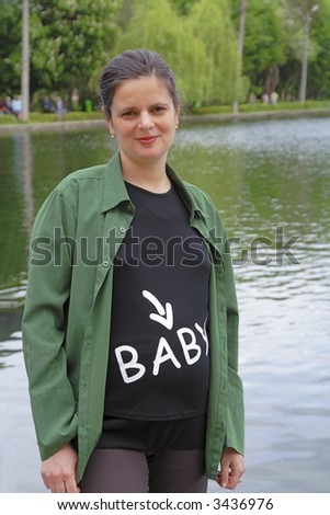 Pregnant woman wearing a funny shirt in a park