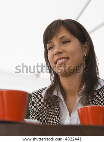Portrait of a young businesswoman at a coffee table with two red mugs- unusual perspective.