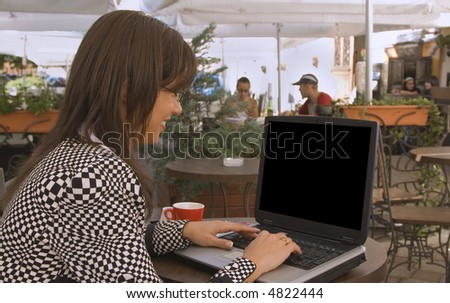 Young woman browsing internet on a laptop at a terrace in a city.The file includes a clipping path on the laptop screen so it is very easy for you to put there something.