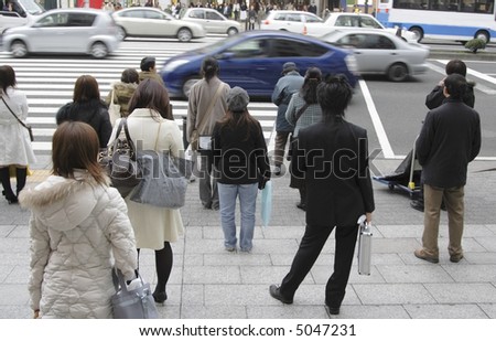 Image of people waiting to cross the street in a big city.