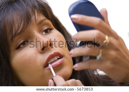 Close-up image of a young woman applying lipstick.