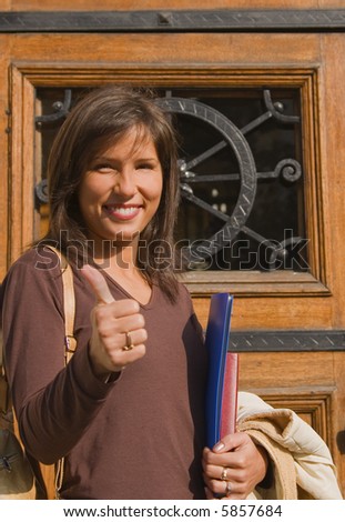 Young student expressing happiness in front of the university door.(good examination results)
