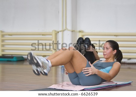 Girldoing aerobics floor exercises in a fitness gym.
