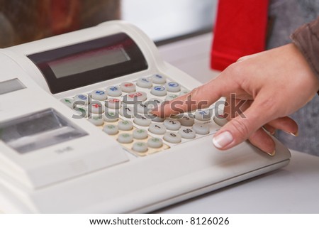 Close-up image of a shop-assistant\'s hand pressing a key of an electronic cash register in a shop.
