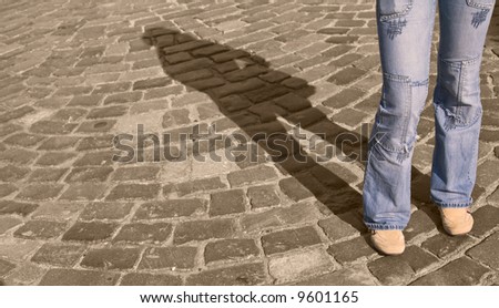 Legs in jeans casting a shadow on a pavement street. Special color management.