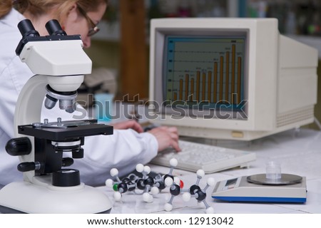 A female researcher analyzing some data at her lab desk.The image on the computer screen is mine.Selective focus on the microscope.
