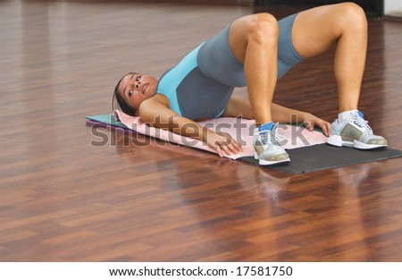 Young woman doing floor exercise in a gym.