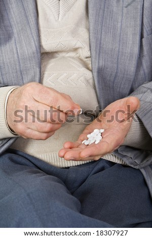 Close-up image of a senior\'s hands taking pills.