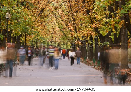 Blurred image of people walking in an autumn park.