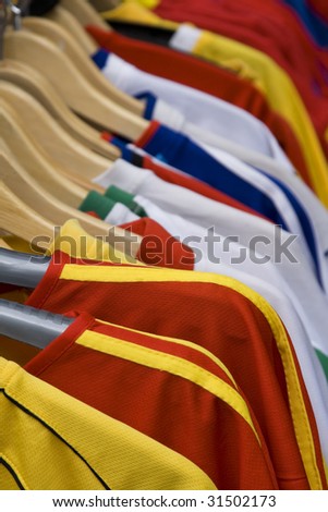 Image of colorful T-shirts on hangers in a street stand.