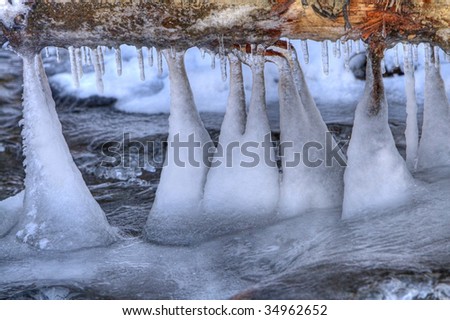 Ice formation on a frozen river under an overturned tree trunk