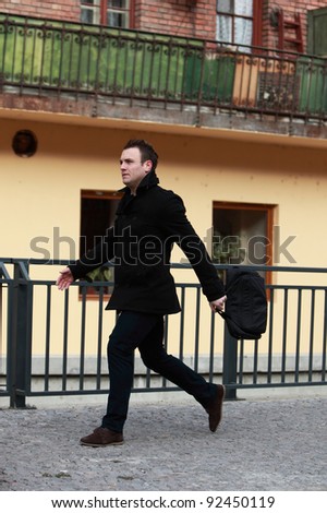 Young casual man in a hurry in a small cobbled city street.